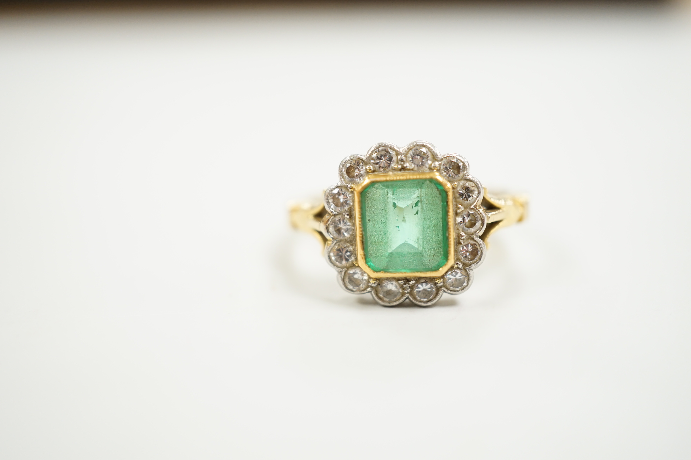 A modern 18ct gold, emerald and diamond set circular cluster ring, size O, gross weight 5 grams.